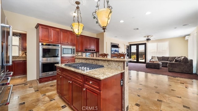 kitchen with pendant lighting, appliances with stainless steel finishes, a center island, french doors, and light stone counters