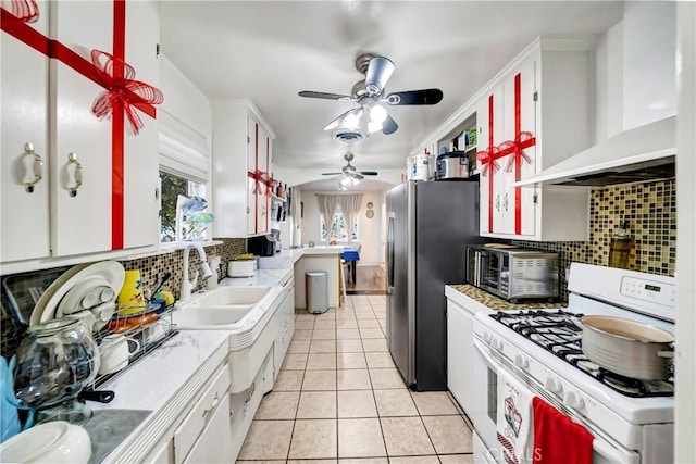 kitchen with backsplash, sink, stainless steel appliances, white cabinets, and wall chimney exhaust hood