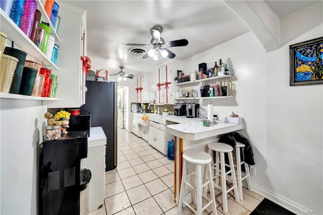 kitchen featuring a breakfast bar area, ceiling fan, light tile patterned flooring, and white cabinetry