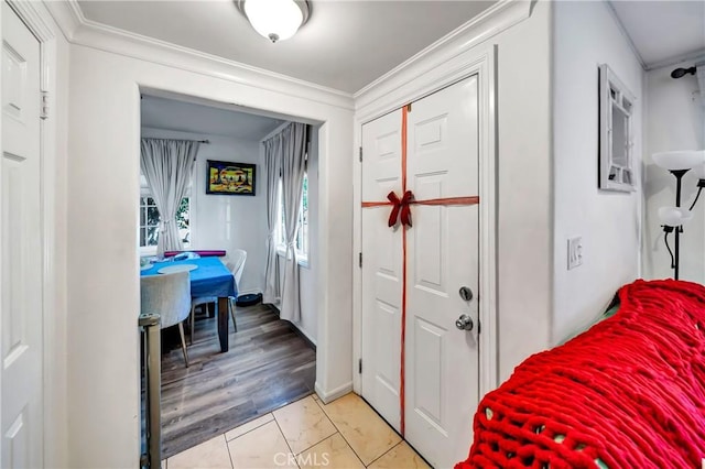 foyer entrance with light tile patterned floors and ornamental molding