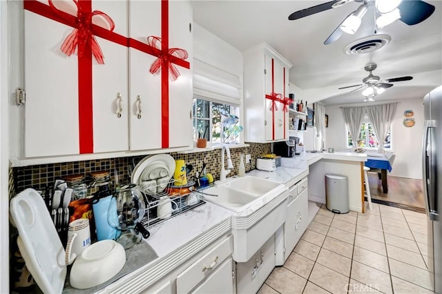 kitchen with light tile patterned floors, white cabinetry, tasteful backsplash, a wealth of natural light, and sink