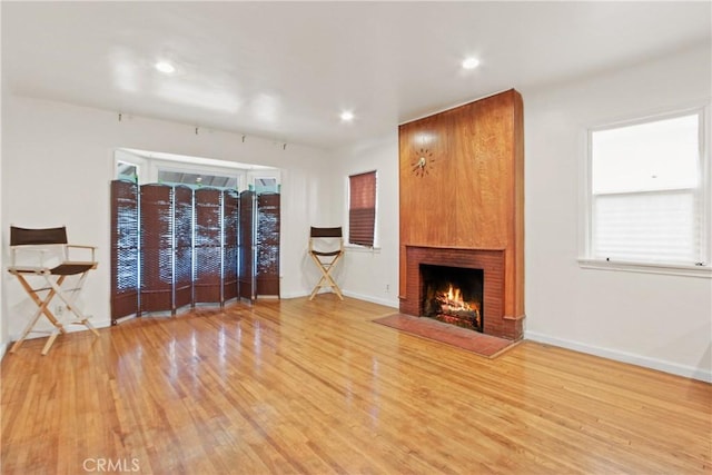 unfurnished living room with a brick fireplace, plenty of natural light, and light hardwood / wood-style flooring