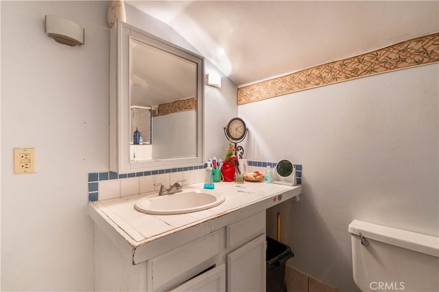 bathroom featuring backsplash, toilet, vanity, and vaulted ceiling