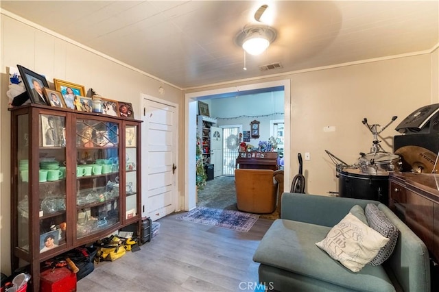 living area featuring hardwood / wood-style flooring and ornamental molding