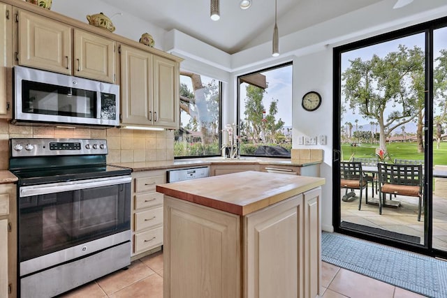 kitchen with light tile patterned floors, appliances with stainless steel finishes, a center island, tasteful backsplash, and vaulted ceiling