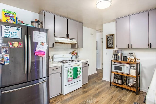 kitchen with gray cabinets, decorative backsplash, wood-type flooring, and white appliances