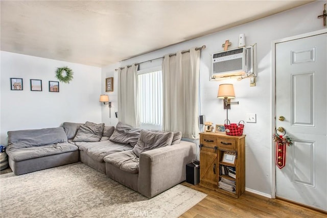 living room with a wall mounted AC and light wood-type flooring