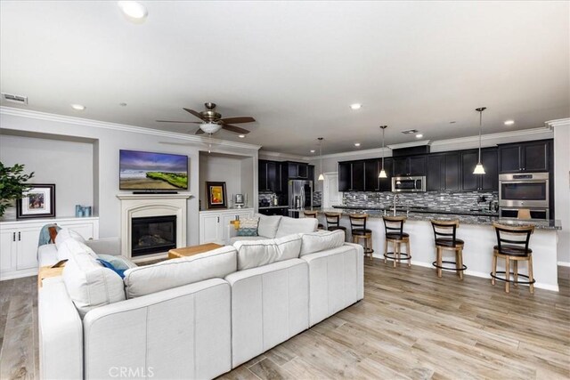 living room with crown molding, light hardwood / wood-style flooring, and ceiling fan