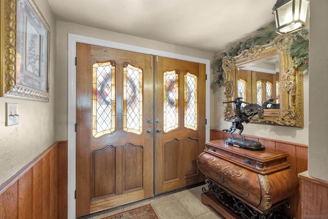 tiled entrance foyer with a healthy amount of sunlight, french doors, and wooden walls