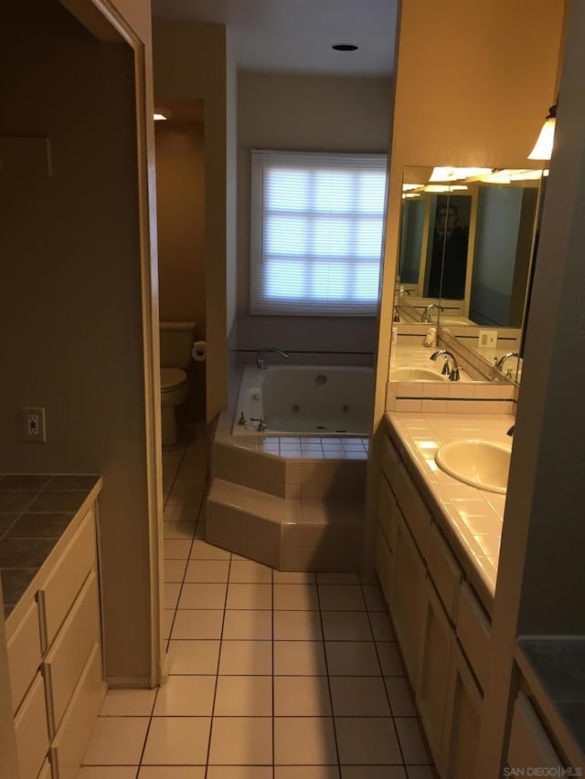 bathroom with toilet, vanity, tile patterned floors, and a relaxing tiled tub