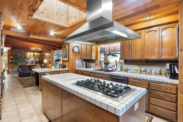 kitchen featuring tile counters, stainless steel gas stovetop, island exhaust hood, and a kitchen island