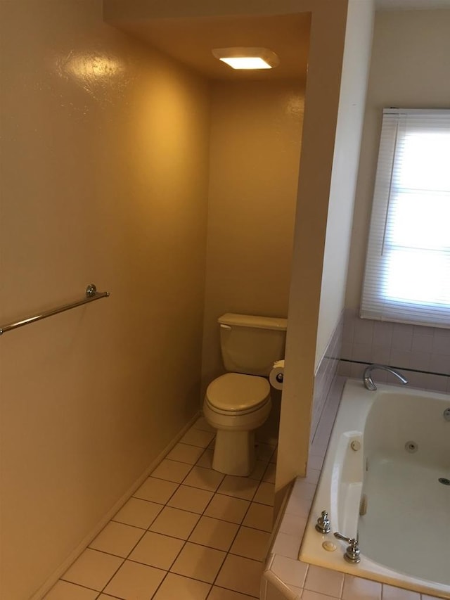 bathroom with toilet, tile patterned floors, and tiled tub