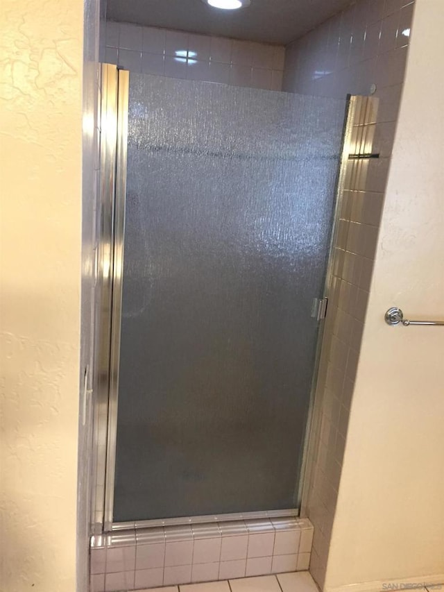 bathroom with a shower with shower door and tile patterned flooring