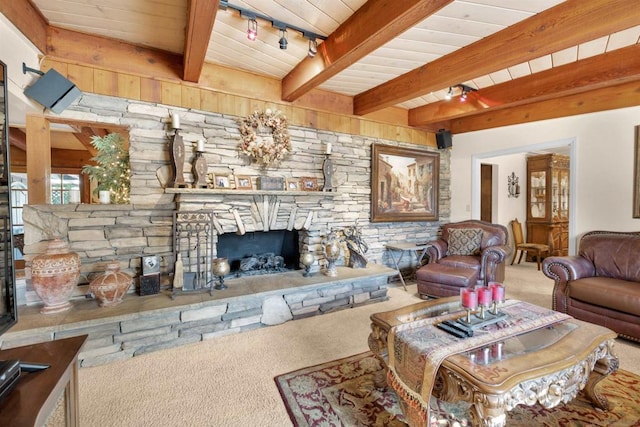 carpeted living room featuring rail lighting, a fireplace, and beam ceiling