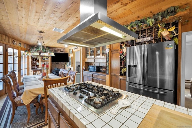 kitchen featuring stainless steel appliances, wooden ceiling, tile counters, and island range hood