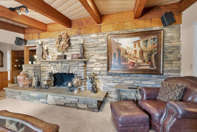 carpeted living room featuring a stone fireplace, beamed ceiling, wooden walls, and wooden ceiling