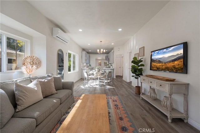 living room featuring dark hardwood / wood-style floors, a wall mounted AC, and an inviting chandelier