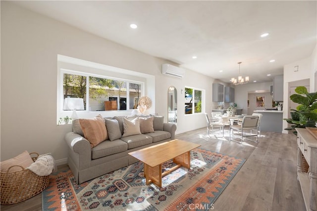 living room featuring a notable chandelier, light hardwood / wood-style floors, and an AC wall unit