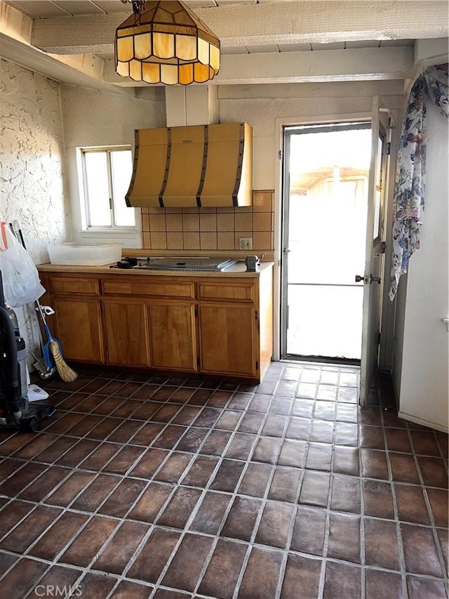 kitchen with light countertops, tasteful backsplash, gas cooktop, and brown cabinets