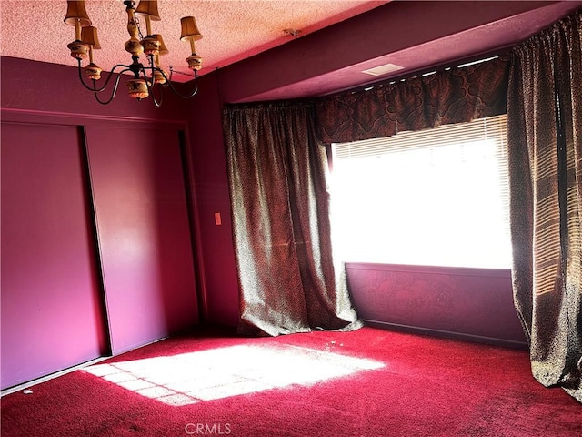 unfurnished room with carpet floors, an inviting chandelier, and a textured ceiling