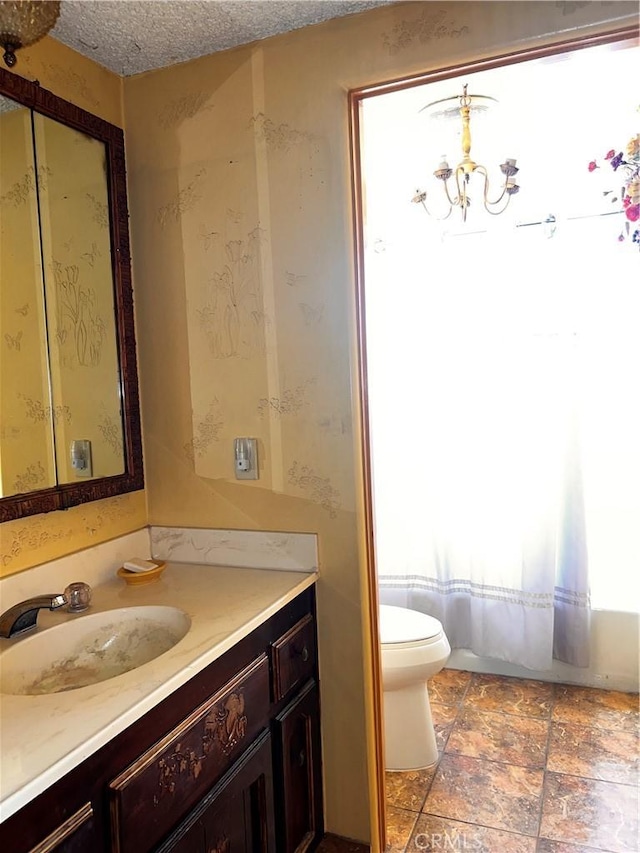 bathroom featuring a textured ceiling, vanity, toilet, and a notable chandelier