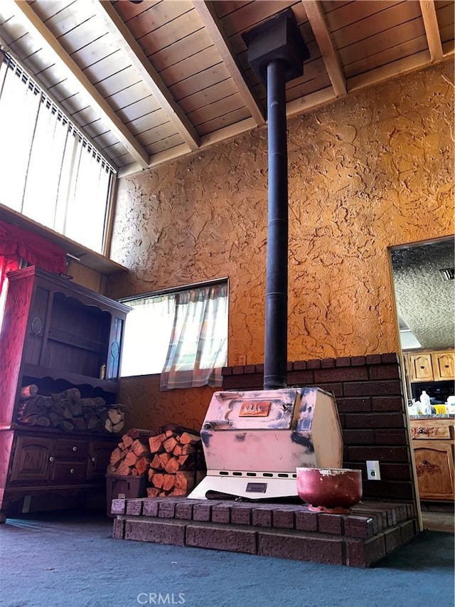 room details featuring beamed ceiling, wooden ceiling, and a wood stove