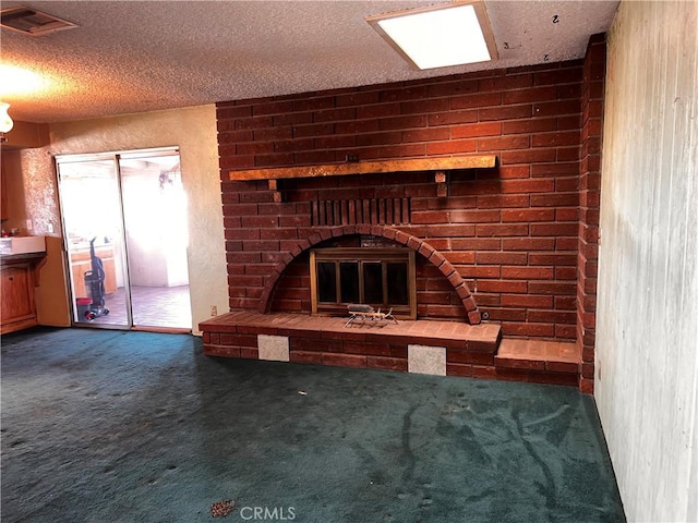 unfurnished living room with a textured ceiling, dark carpet, a fireplace, and visible vents