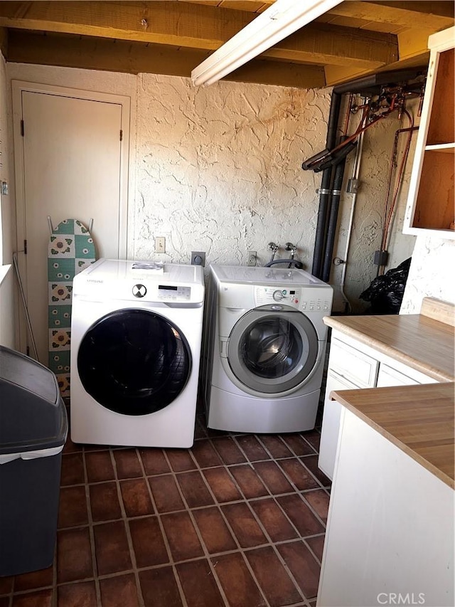 clothes washing area with laundry area, dark tile patterned floors, separate washer and dryer, and a textured wall