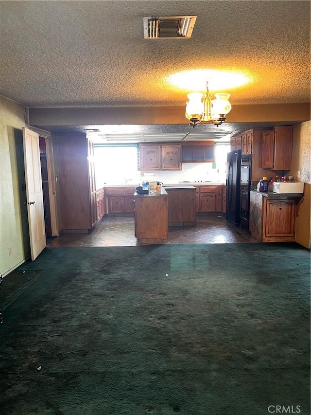 kitchen featuring a kitchen island, visible vents, dark colored carpet, and freestanding refrigerator