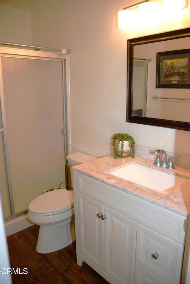 bathroom with vanity, toilet, hardwood / wood-style floors, and a shower with shower door