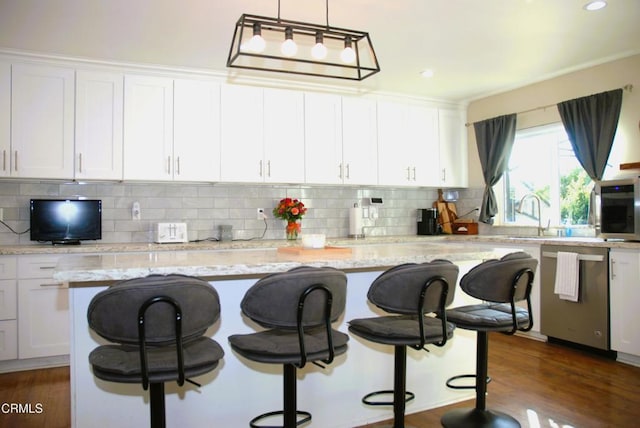 kitchen featuring white cabinetry, a kitchen island, a breakfast bar area, and decorative light fixtures