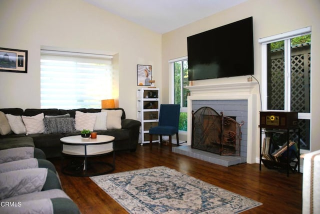 living room featuring vaulted ceiling, dark hardwood / wood-style floors, and a fireplace