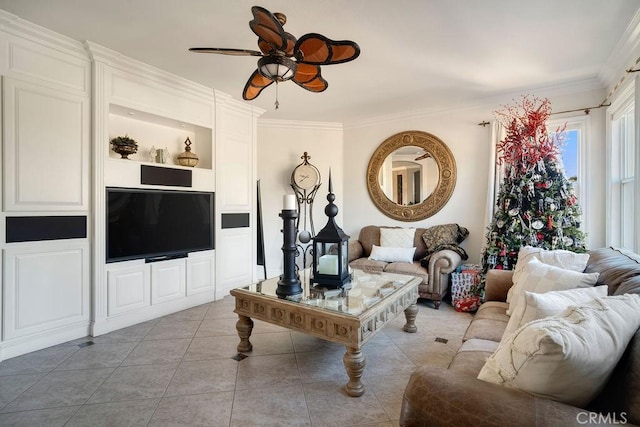 living room featuring ceiling fan, built in shelves, light tile patterned floors, and crown molding