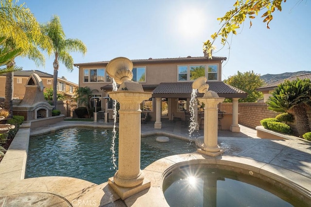 view of swimming pool with pool water feature, an outdoor fireplace, exterior bar, and a patio area