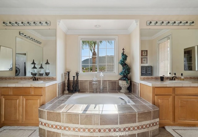 bathroom featuring ornamental molding, tiled tub, and vanity