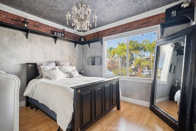 bedroom with brick wall, light hardwood / wood-style flooring, and a notable chandelier