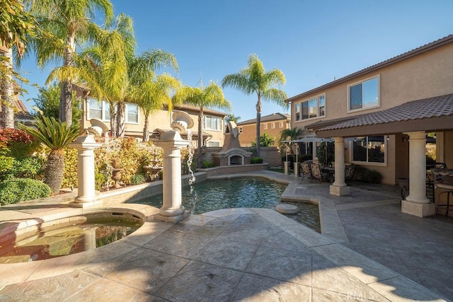 view of swimming pool with exterior fireplace, a patio, and an in ground hot tub