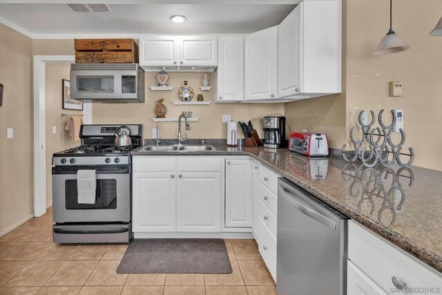 kitchen featuring sink, light tile patterned floors, hanging light fixtures, appliances with stainless steel finishes, and white cabinets