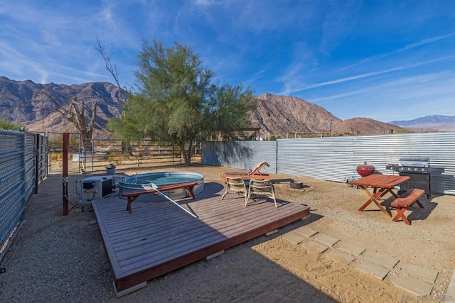 view of patio / terrace featuring grilling area, a hot tub, and a deck with mountain view