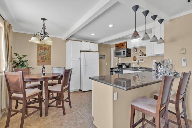 kitchen featuring beamed ceiling, hanging light fixtures, appliances with stainless steel finishes, white cabinets, and a chandelier