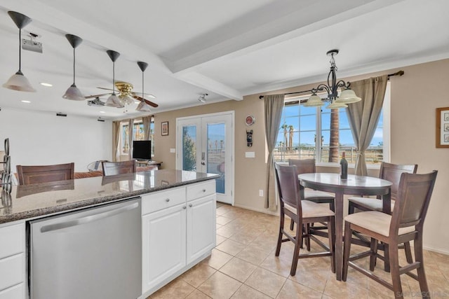 kitchen with stainless steel dishwasher, white cabinets, dark stone countertops, and hanging light fixtures