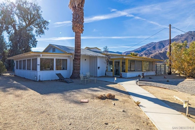 view of front of property with a patio area, a sunroom, and a mountain view