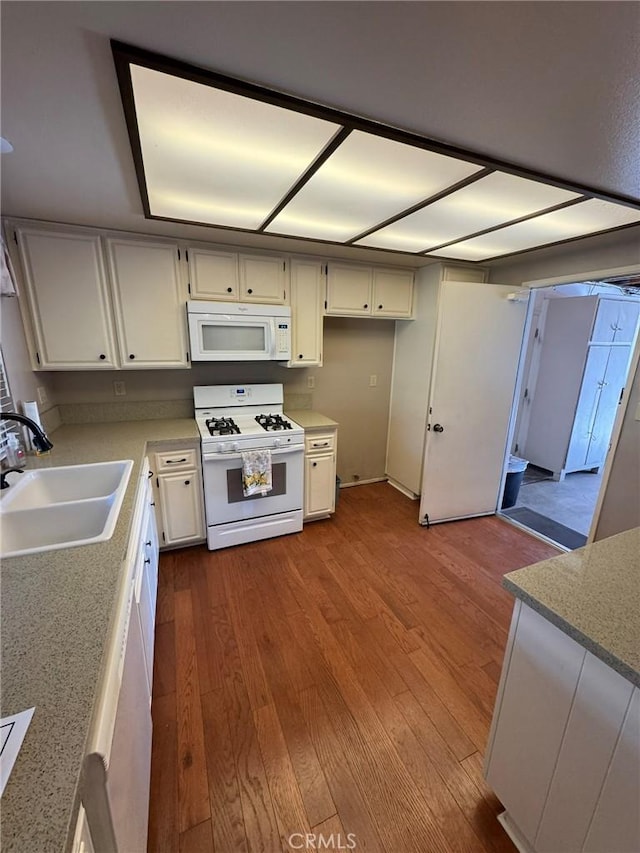 kitchen with wood-type flooring, sink, white appliances, and white cabinets