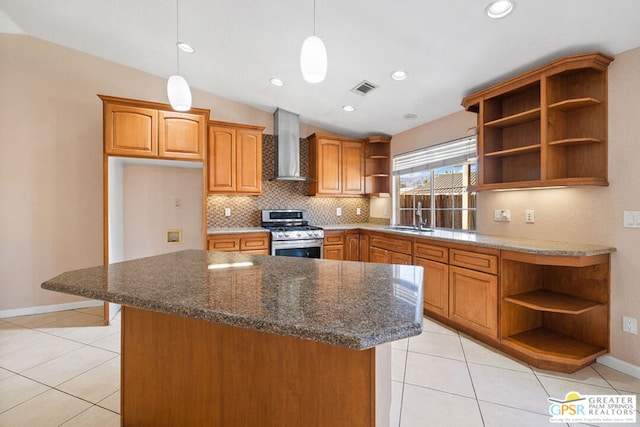 kitchen featuring gas stove, lofted ceiling, wall chimney range hood, pendant lighting, and sink