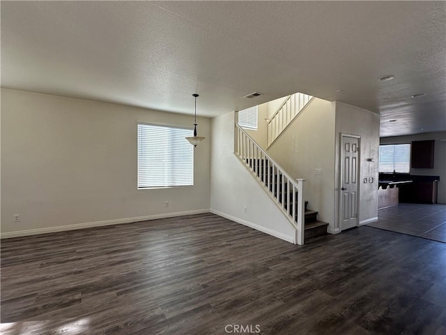 unfurnished living room featuring dark hardwood / wood-style flooring and a textured ceiling