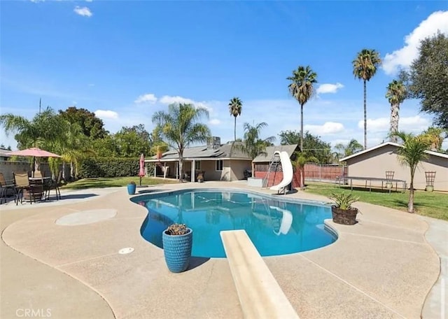 view of pool with a diving board, a patio area, and a water slide