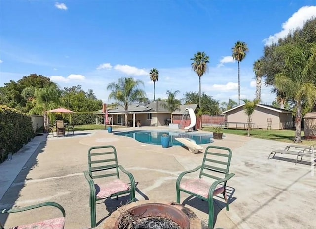 view of swimming pool featuring an outdoor fire pit, a water slide, and a patio