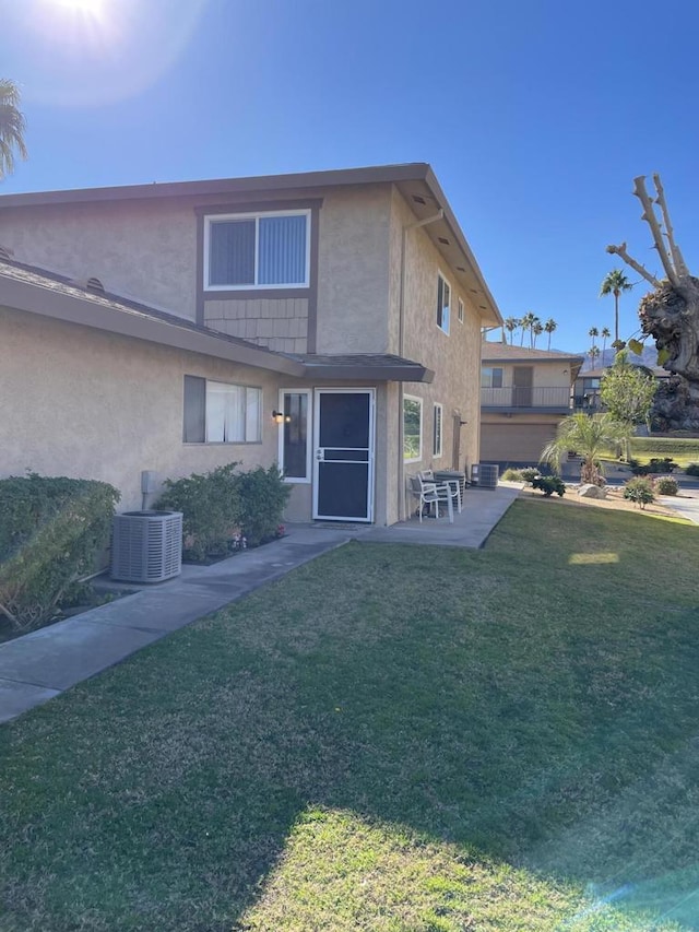 rear view of property featuring a lawn, cooling unit, and a patio