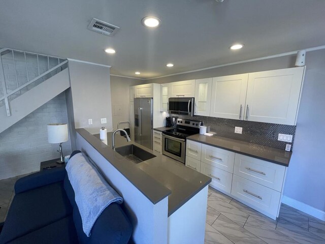 kitchen with backsplash, a breakfast bar, sink, appliances with stainless steel finishes, and white cabinets