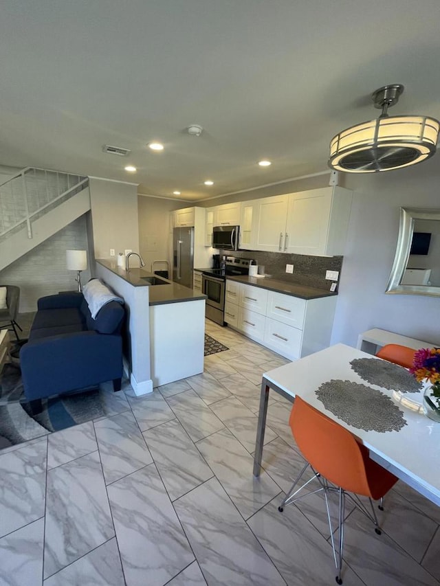 kitchen featuring backsplash, kitchen peninsula, sink, appliances with stainless steel finishes, and white cabinets